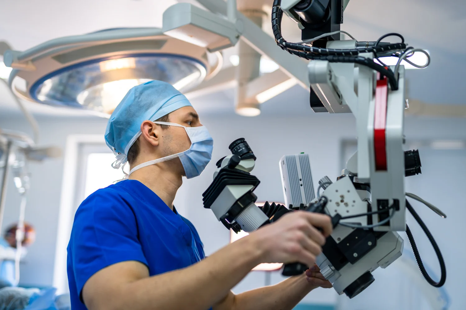 Surgeon in scrubs and a mask using an operating microscope