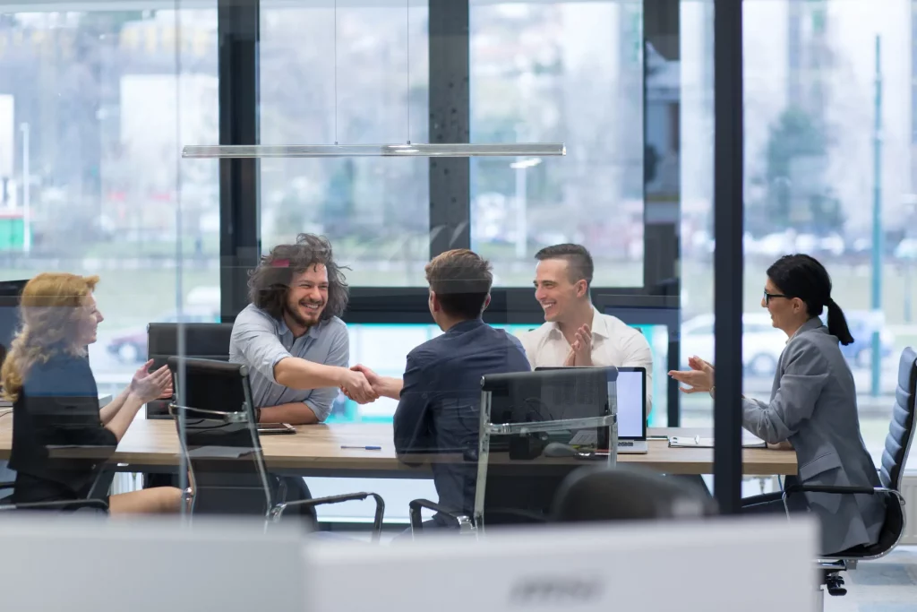 Team celebrating a successful handshake during a leadership development meeting.